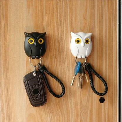 Owl-shaped magnetic key holders in black and white, securely holding keys on a wooden surface.