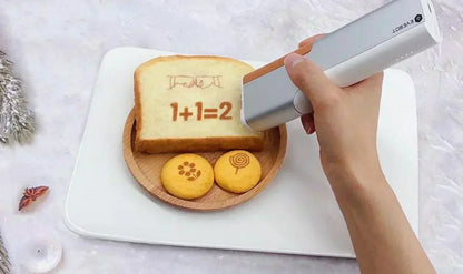 Person using EVEBOT Portable Inkjet PrintPen to decorate food items with edible ink designs.